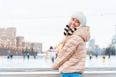 Büyük şehrin güzel kızı, komik pofuduk şapkalarla caddede dikilirken mutlu kış zamanları. Kar yağışı, pozitiflik, kameraya gülümseme, neşeli ruh hali, gerçek duygular, Noel havası.