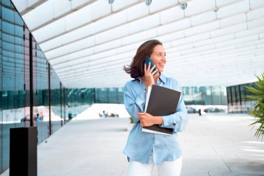 Excited caucasian businesswoman standing near office building have phone conversation feeling surprised Happy female worker happy smile after hear good news. positive cell phone conversation