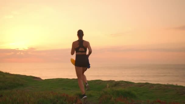 Γυναίκα Τζόκινγκ Στη Φύση Τρέχει Στο Ηλιοβασίλεμα Πίσω Όψη Κρατώντας — Αρχείο Βίντεο