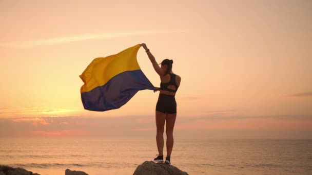 一个举着乌克兰国旗站在山上的女人 乌克兰战争中 中年人适合悬挂乌克兰国旗的女性对抗日落支持 为乌克兰祈祷 — 图库视频影像