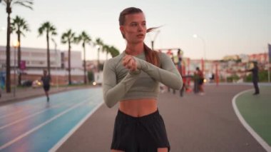 Koşu parkurunda koşmadan önce esneme ve ısınma hareketleri. Formda sporcu kadın vücudunu ısıtıyor. Yaz akşamları spor giyinen kız dışarıda egzersiz yapıyor. 