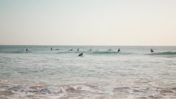 ポルトガル カルカベロス 2022年10月大西洋で波に乗るウェットスーツのサーファーのグループカルカベロスビーチ夏の日 アマチュアサーフィンライダーグループ — ストック動画