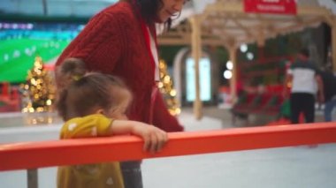 Anne ve kızı buz pateni pistinde iyi eğlenceler. Buz pateni yardım yunusu kullanın. Annesi küçük kızına paten kaymayı öğretiyor. Kış Noel buz pateni pisti kış sporları, açık havada aktif boş günler.