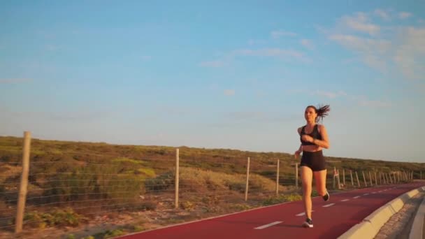 夏の朝に競馬場を走る女 中世の白人女性が道路の近くを走る道を走っている ジョギングはゆっくりとした動きは撮影後に実行します 運動40年外の女性のジョギング — ストック動画