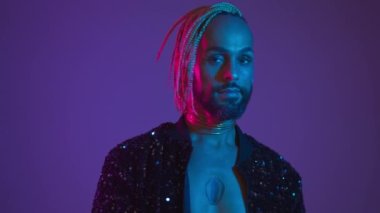 Neon light studio close-up portrait handsome black gay man looking camera. Seductive brazilian man wear make up, transgender person in ultraviolet light. LGBT nightclub and nightlife concept