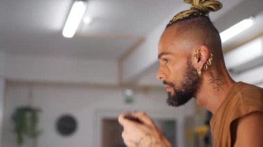 Handsome homosexual man with beard who applies powder to his face. LGBT community with freedom for homosexuals. Black male gay transgender model. The rights of sexual minorities. Gender Diversity