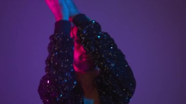 Neon light studio close-up portrait handsome black gay man looking camera. Seductive sexy man wear make up, transgender person dance in ultraviolet light. LGBT nightclub dancer nightlife concept 