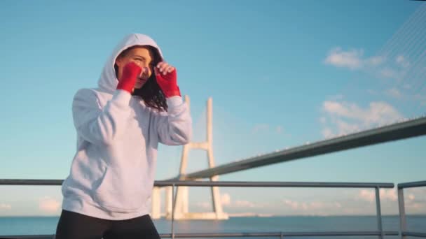 Женщина Боксирует Руками Завернутыми Красные Боксерские Ленты Океанским Мостом Голубым — стоковое видео