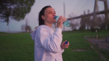 Female boxer resting after boxing workout drink water from plastic bottle. Fitness, sports, or wellness motivation. Tired, sweaty, proud female boxer resting after intense workout session.