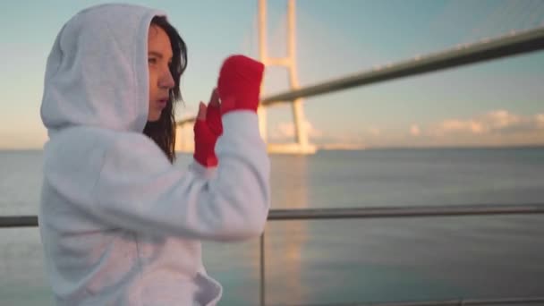 Женщина Тень Боксирует Руками Завернутыми Красные Боксерские Ленты Океанским Мостом — стоковое видео