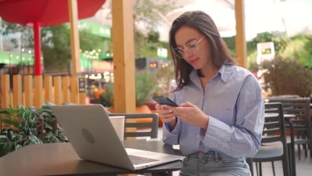 Жінка Використовує Терасу Кафе Ноутбуком Жінка Окулярах Використовує Мобільний Телефон — стокове відео