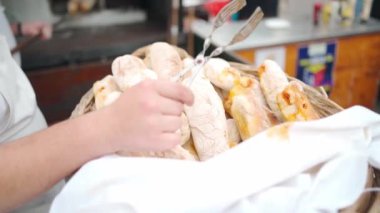 Street vendor puts meat pies in basket for sale. Close up hands of outdoor pastry seller with fresh homemade pies in wooden basket