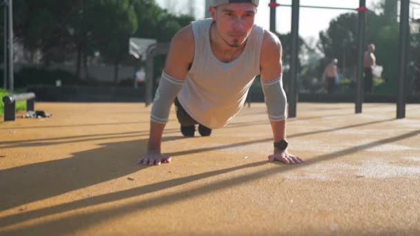 运动员在公园的运动场上做推拿运动 在阳光明媚的夏日 白人男性运动员在体育馆外加紧锻炼 — 图库视频影像