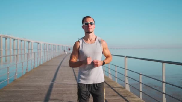 男ジョギング橋晴れた日の青空の背景を実行している 運動選手はカーディオトレーニングを行います ジョグ演習朝の活動 健康的なフィットネスライフスタイルスローモーションハンドヘルド効果 後を追え — ストック動画
