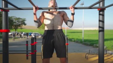 Atletik adam yatay barın önünde durur. Üstsüz erkek sporcu parkta spor sahasında. Fitness, spor, güç egzersizi, eğitim ve yaşam tarzı kavramı