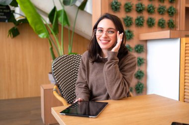 Modern technologies and communication. Portrait of happy woman with tablet computer sitting at her desk. Young female person studying or working online on touch pad clipart