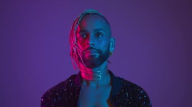 Neon Light Stüdyoları yakın plan yakışıklı zenci gay adam kamerası. Baştan çıkarıcı seksi adam makyaj yapıyor, transseksüel insan ultraviyole ışıkta. LGBT gece kulübü dansçısı konsepti 