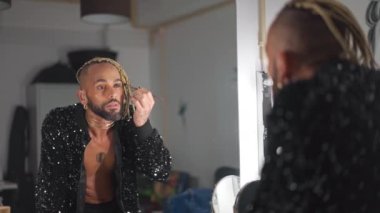 Eşcinsel adam aynaya bakarak kirpik sürüyor. Brezilyalı siyah etnik kökenli sakallı homoseksüel adam makyaj yapıyor. Çift cinsiyetli olmayan kişi. LGBT insanları cinsiyet kimliği, makyaj ve yaşam tarzları kavramları