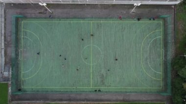 Mini futbol sahasının havadan insansız hava aracı görüntüsü, yol kenarında insanlarla oynayan yapay plastik kaplı. Güneşli yaz günü insansız hava aracı manzaralı şehirde halka açık bir spor alanı.