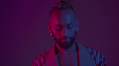 Neon Light Stüdyoları yakın plan yakışıklı zenci gay adam kamerası. Baştan çıkarıcı seksi adam makyaj yapıyor, transseksüel insan ultraviyole ışıkta. LGBT gece kulübü ve gece hayatı konsepti