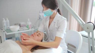 Parlayan, pürüzsüz ve sağlıklı cilt bakımı estetik estetik salonu için kadınlara yüz masajı. Güzellik, detoks ve eller genç müşteriyi yüz terapisi seansında iyileştirir.