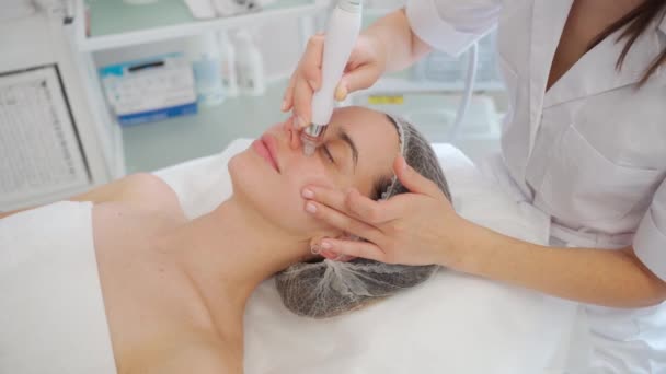 水はけの美しさの手順 顔のクリーニング きれいな肌 美容クリニックでの女性患者 美容クリニックでの美容手順を実行する医師 美容師のクリーニング患者の顔 — ストック動画