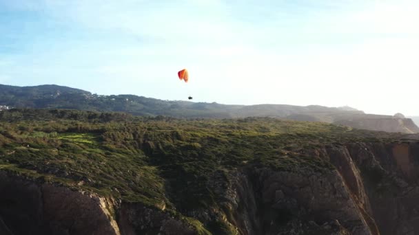 在蔚蓝的天空中飞行的极致的滑翔伞 向着电影般的沉闷的海洋飞去 无法辨认的人带着芦笋在大西洋附近飞行 — 图库视频影像