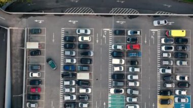 Farklı arabalarla dolu bir alışveriş merkezinin park süresi dolmuş. Modern araçlar kalabalık park alanına girip çıkıyorlar.