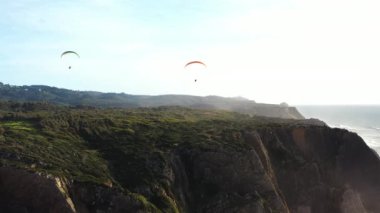 Uçsuz bucaksız mavi gökyüzünde, sinematik deniz mavisi okyanusuna doğru uçan olağanüstü bir paraglider. Tanınmayan kişi Atlantik Okyanusu yakınlarında paraşütle uçuyor.