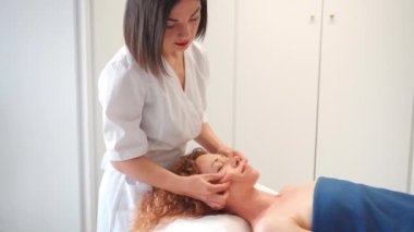 Masaj terapisti. Kozmetoloji kliniğinde kafa, omuz ve boyuna masaj yapıyor. Cilt bakımı ve canlandırma prosedürü yapan bir güzellik uzmanı. Güzellik salonunda kaplıca tedavisi ve masaj.
