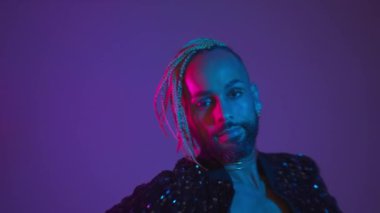 Neon light studio close-up portrait handsome black gay man looking camera. Seductive sexy man wear make up, transgender person dance in ultraviolet light. LGBT nightclub dancer nightlife concept 