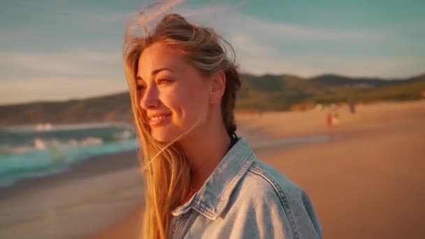 Жінка Посміхається Дивлячись Камеру Стоїть Березі Океану Вітер Дме Волосся — стокове відео