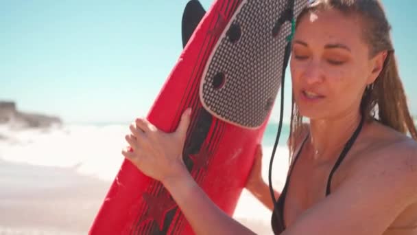 海上での夏休みにサーフィンの練習をしている女性観光客 遊び心のあるサーファーの女性が水からサーフボードを引っ張って笑っている 旅行休暇中の健康的なアクティブなライフスタイル — ストック動画