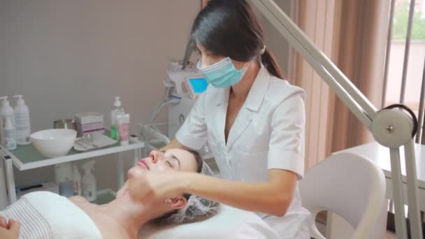 医疗面罩按摩治疗师在美容外科诊所为妇女按摩头 肩膀和脖子 美容师制定护肤和刺激程序 美容院温泉治疗及按摩 — 图库视频影像