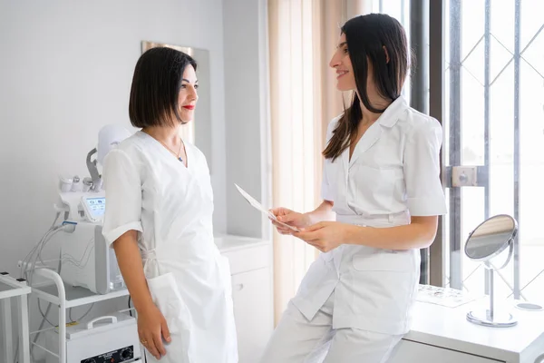 Дві Жінки Лікарі Стоять Медичній Клініці Обговорюючи Результати Іспитів Пацієнта — стокове фото