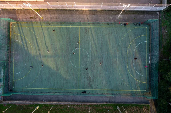 Aerial drone top view of mini football soccer field with artificial plastic cover with playing people. Public sport ground in city at sunny summer day drone view. Portugal