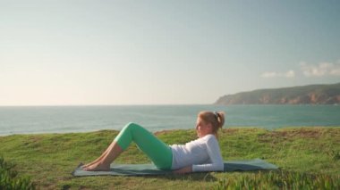 Yoga yapan emekli kadın, okyanus kıyısında halasana pozu veriyor. Sağlıklı omurga ve kadın sağlığı için pilates çalışması. Güneşli bir sabahta Zindelik 