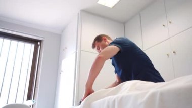 Klinikte profesyonel terapi masajı. Masör masaj odasında masaj masasında yatan sırt ve omuz masajı yapan kadın hasta. Sağlık hizmetleri kavramı