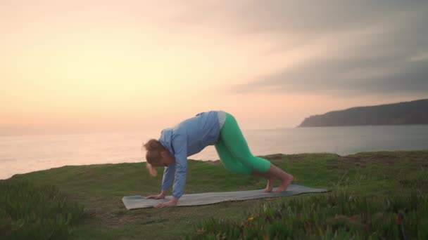 老年妇女在海滩上练习瑜伽 退休妇女在日落时练习瑜伽 伸展她的身体海洋背景 健康的概念 健康的老年生活方式 瑜伽姿势 — 图库视频影像