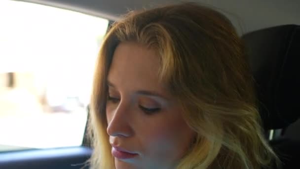 迷人的高加索年轻女子坐在轿车后座上的人脸肖像 有信心的年轻女子在旅途中使用转机服务 坐出租汽车时坐在后座上 — 图库视频影像