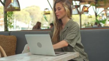 Caddedeki kafede dizüstü bilgisayarda yazan neşeli kadın blogcu. Zarif gözlüklü, kendine güveni tam genç bir kadın. Yazın açık kafe terasında yeni blog için dizüstü bilgisayarda yazı yazıyor. Blogcu blog yazmak için açık havada yazıyor