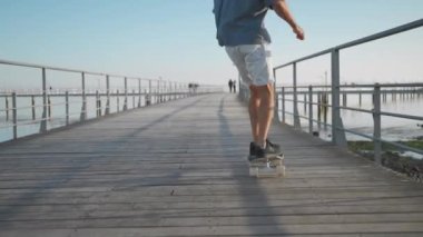 Erkek kaykaycı köprüden nehre atlıyor. Kaykay süren bir adam sol bacağıyla itiyor. Kaykaycı ustalıkla gemiye biniyor. Dikiz aynası. Tam uzunluk