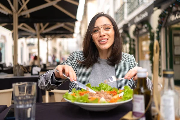 Kafe masasında salata yiyen gözlüklü bir iş kadını. Güzel orta yaşlı bir kadın güzel bir restoranda taze salata yiyor..