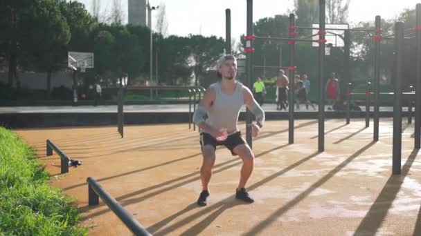公園でスカートワークをしている男 男性アスリートは 低体の筋肉のためのエクササイズを行います スクワットジャンプ プランク 回転でトレーニング中に運動選手 健康的なライフスタイルのコンセプト — ストック動画
