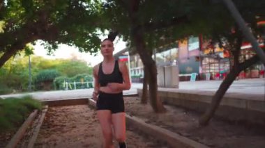 Parkta koşan bir bayan sporcu. Doğal ortamda sabah koşusu yapan atletik bir kadın. Kadın koşucu dışarıda günlük idman yapıyor. Spor ve spor yaşam tarzı konsepti