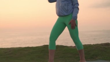 Son sınıf öğrencisi gün batımında hatha yogası yapıyor. Emekli kadın dışarıda Asana 'yı rahatlatıyor. Sağlıklı yaşlı yaşam tarzı. Kişisel bakım konsepti. Dikey çekim