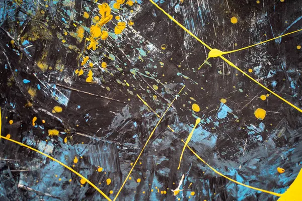Abstract stains of paint on black wall. Showcases abstract splashes of blue and yellow paint. Black surface adorned with artistic paint splotches.