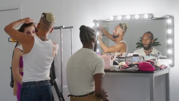 化妆师把化妆品涂在坐在镜子前的女人身上 她是个留着胡子的同性恋模特 男演员和女歌手为自己的工作做后台准备 — 图库视频影像