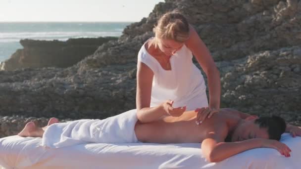 专业的女按摩师为躺在桌子上的黑发女人做按摩 暑假期间的背部按摩 健康的生活方式和身体护理 — 图库视频影像