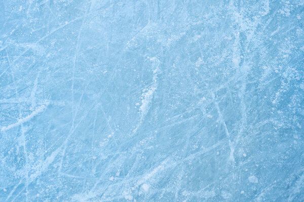 Icy background on rink with visible traces of skating, showcasing the essence of winter sport. Texture of ice on skating rink visible from top view, displaying sheet of scratched ice.
